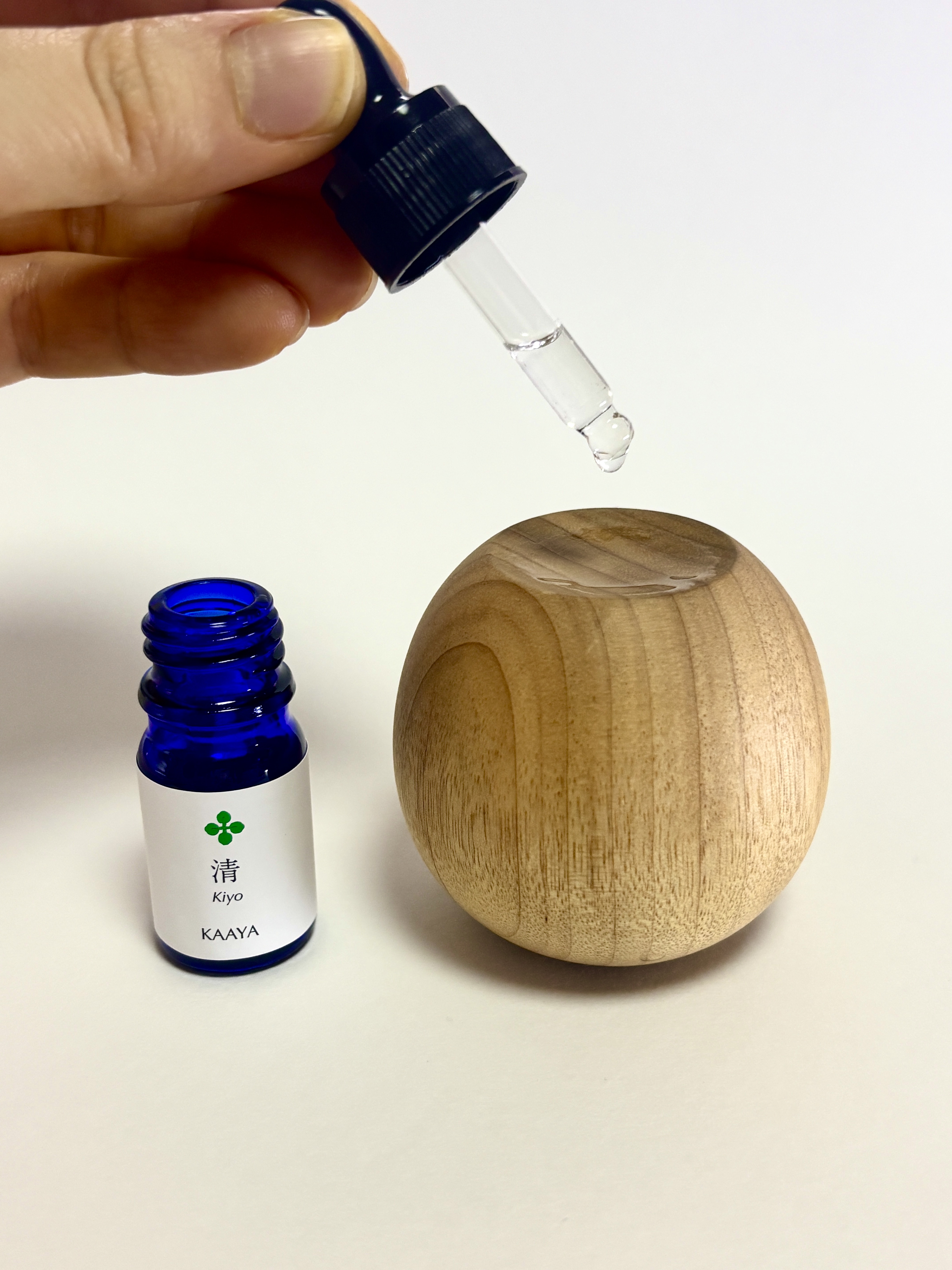 A drop of Kiyo fragrance oil being placed onto a wooden diffuser